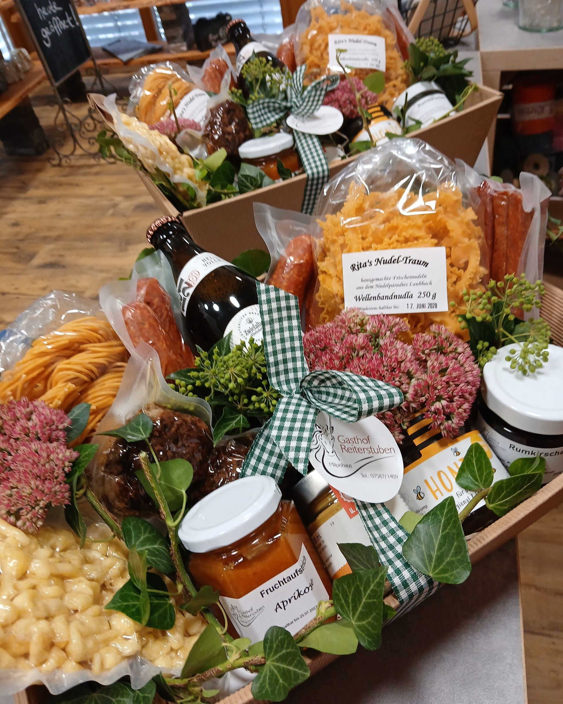 Geschenkkorb mit Nudeln, Fruchtaufstrich, Flasche und grün-weißer Schleife