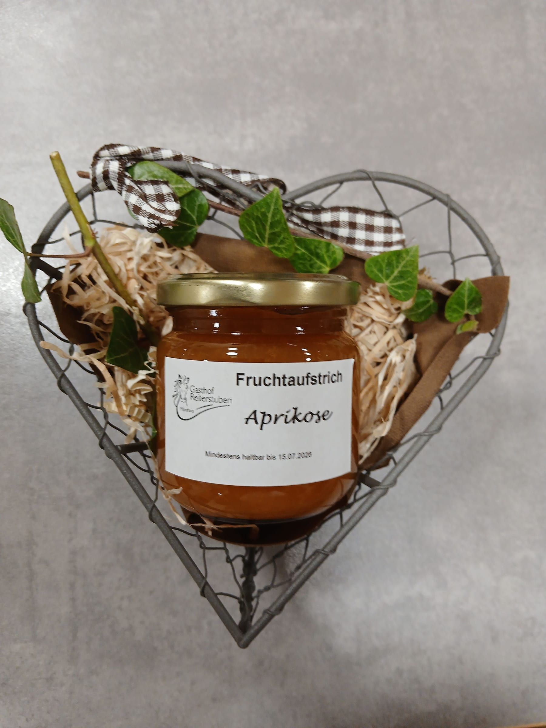 Glas Aprikosen-Fruchtaufstrich in einem Herzkorb