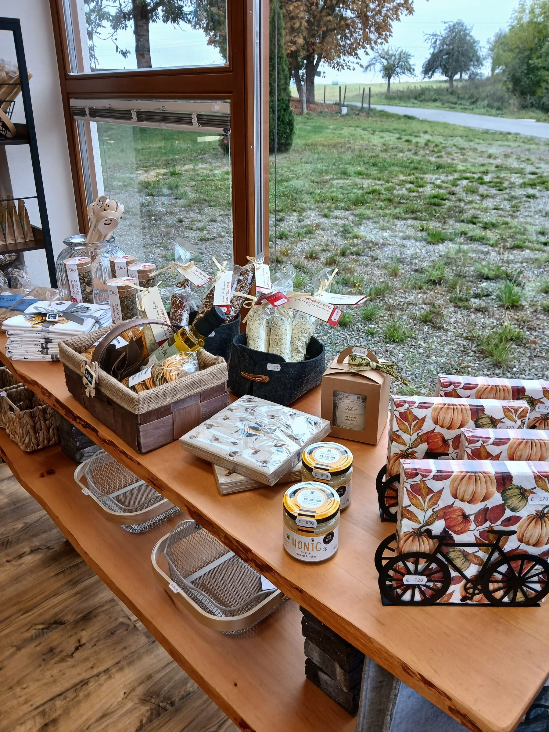 Holztisch mit Honig, Servietten und Geschenkartikeln vor dem Fenster