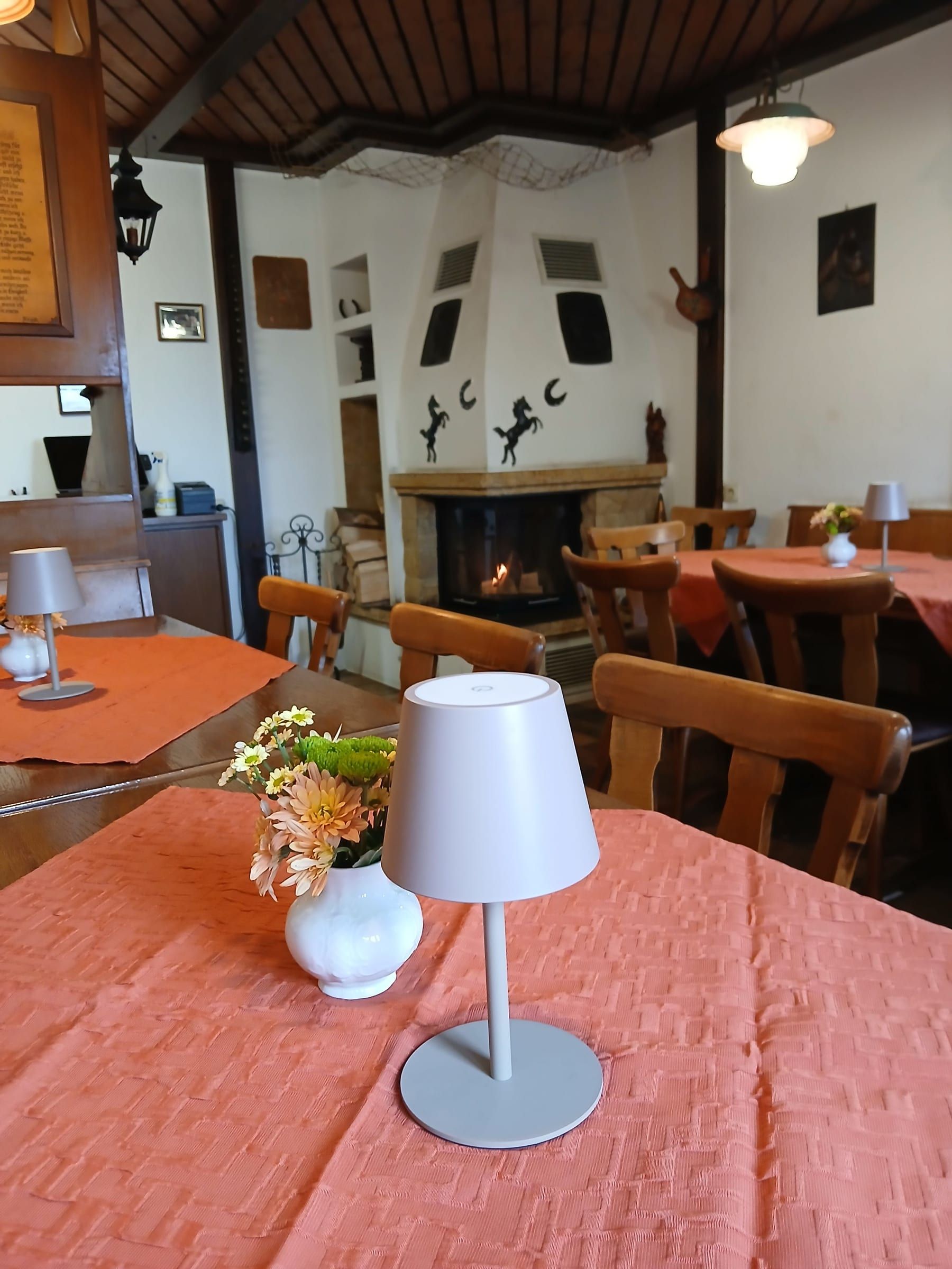 Kaminzimmer mit brennendem Eckkamin und gedeckten Tischen