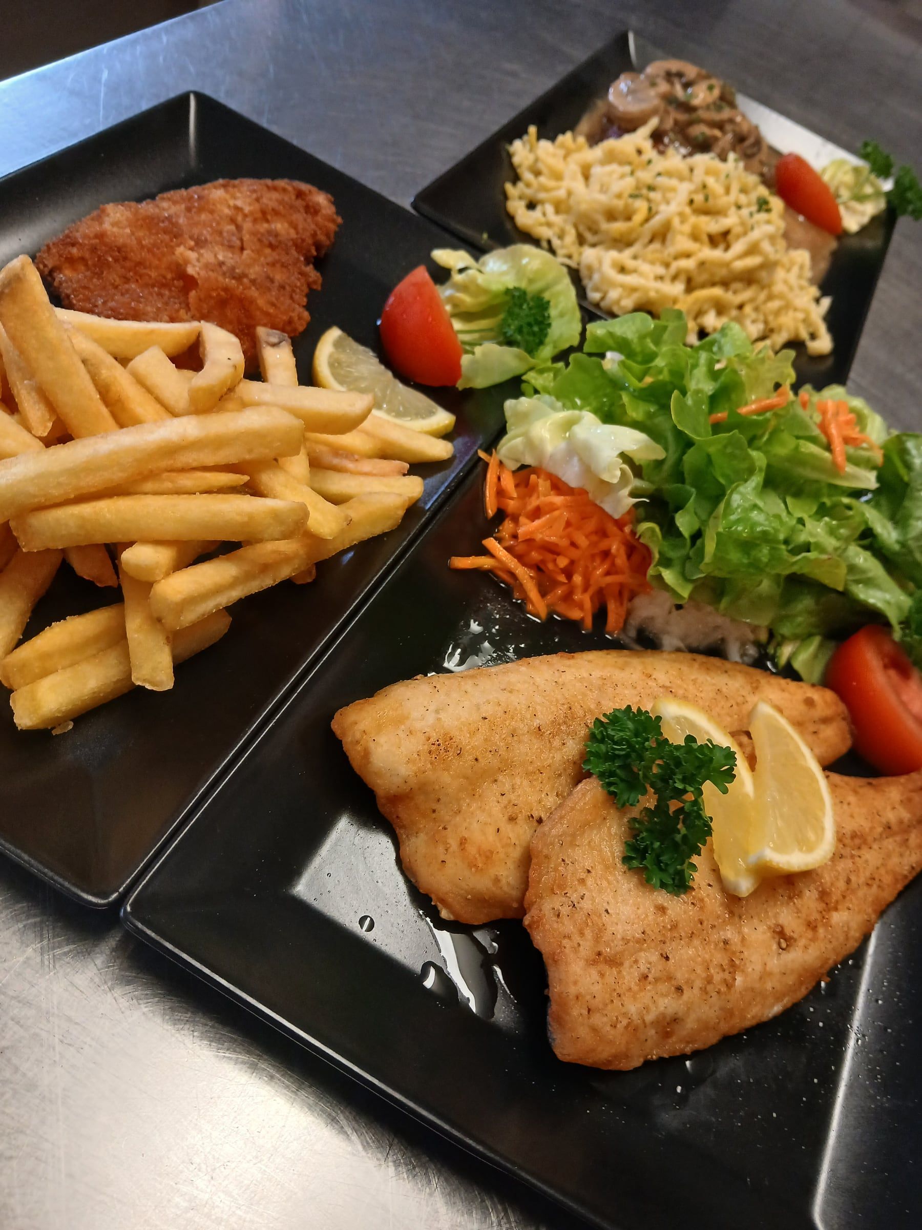 Schnitzel mit Pommes, gebratenes Fischfilet mit Salat und Spätzle mit Pilzsoße