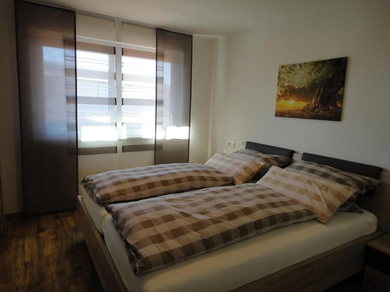 Schlafzimmer mit Doppelbett und karierter Bettwäsche