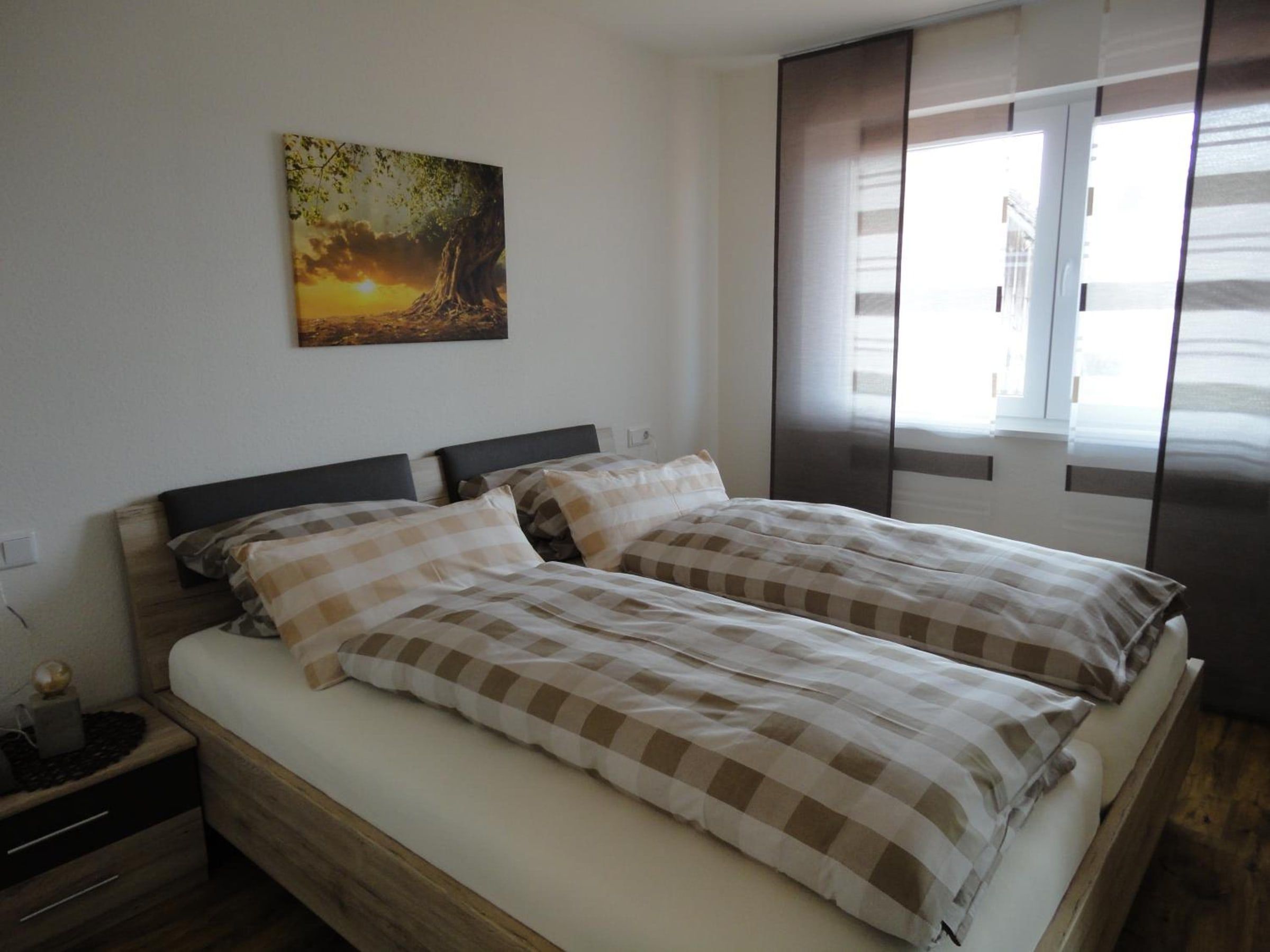 Schlafzimmer mit Doppelbett und Schiebevorhängen am Fenster