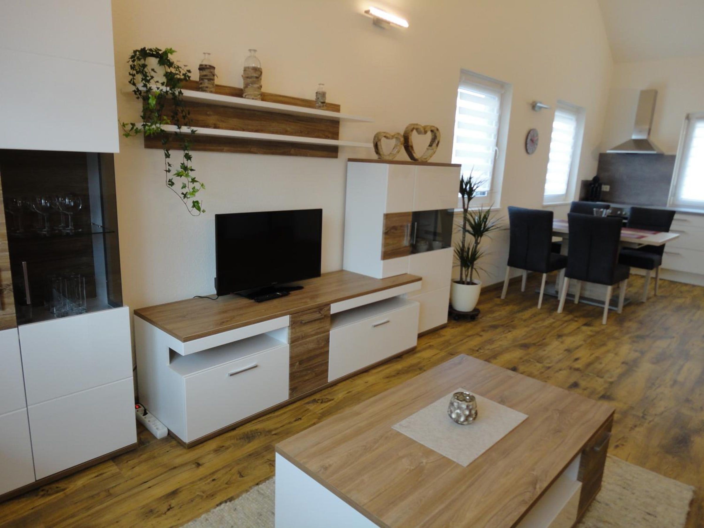 Wohnwand mit Fernseher, dahinter Essplatz und Küche